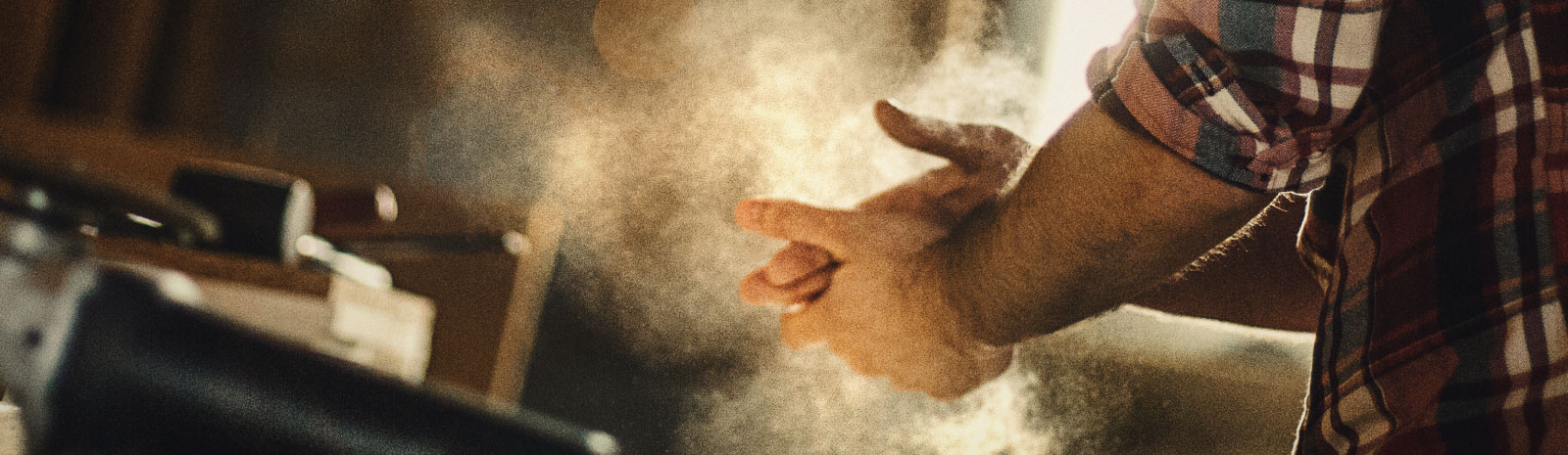 Close-up of a man dusting off sawdust from his hands