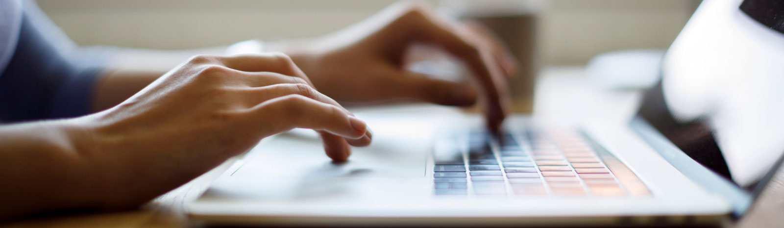 close up of hands using a laptop keyboard