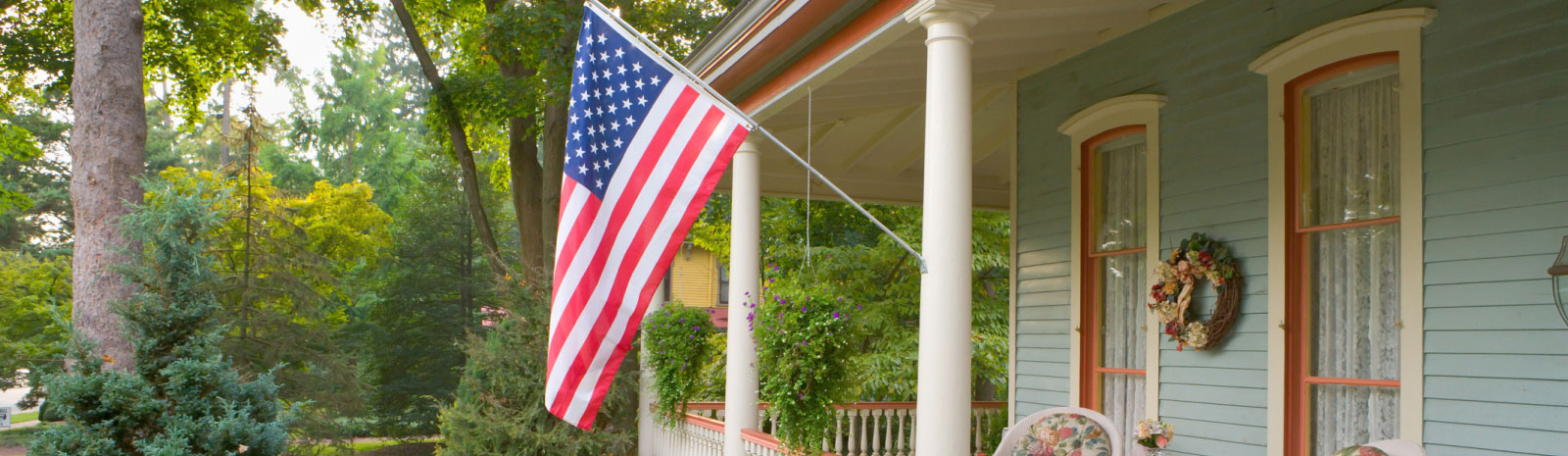 the porch of a suburban home with an american flag on the front